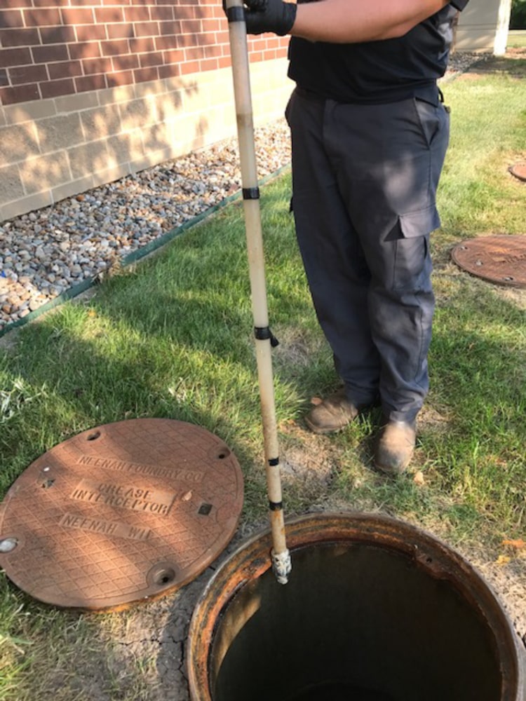 man cleaning inside of grease interceptor